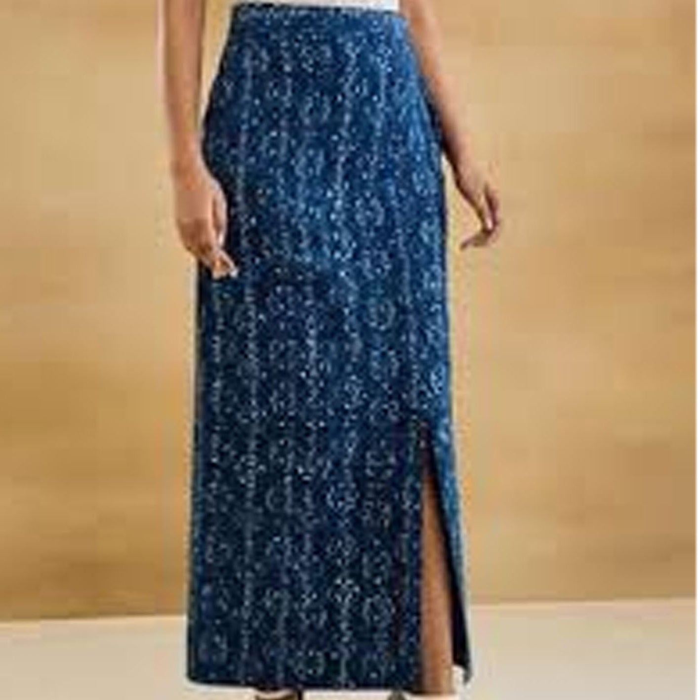 Long blue patterned skirt worn by a person on a beige background