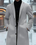 Person wearing a long gray coat with a blurred indoor background