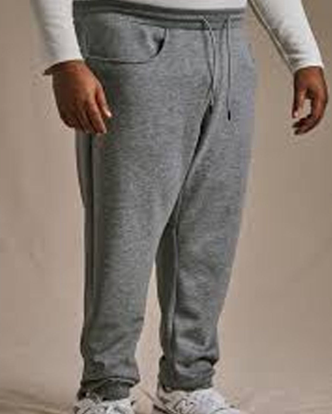 Person wearing gray sweatpants on a beige background
