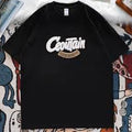 A black short-sleeve t-shirt with a white 'Coutain' graphic and a gold '100% ORGANIC' banner on the chest, laid flat on a patterned blanket.
