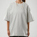 Person wearing a light gray oversized t-shirt on a plain background