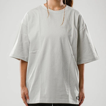 Person wearing a light gray oversized t-shirt on a plain background