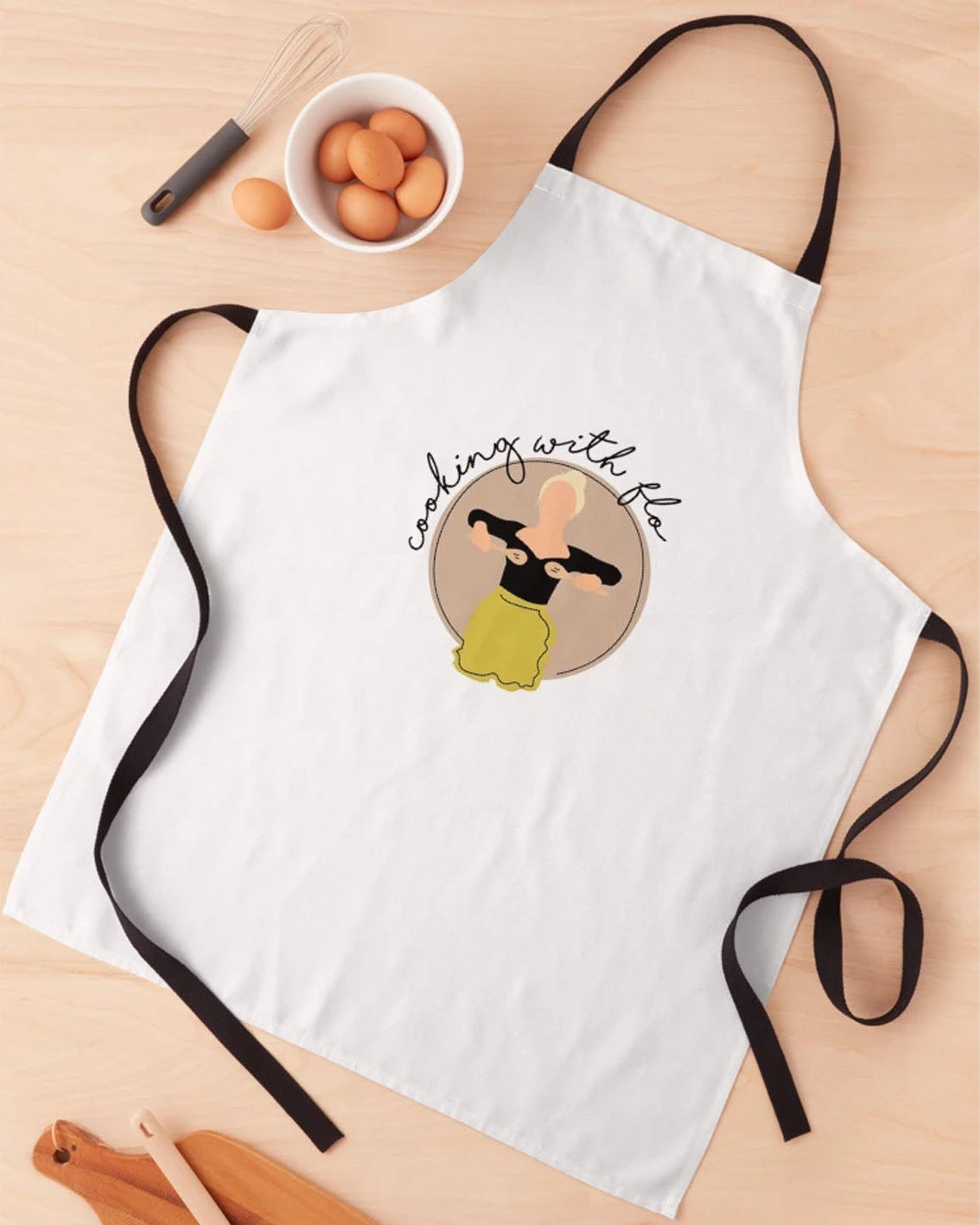 White apron with a design and text on a wooden surface with kitchen items.