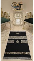 Decorative black and white patterned rug on a marble floor with chairs and a table in the background.