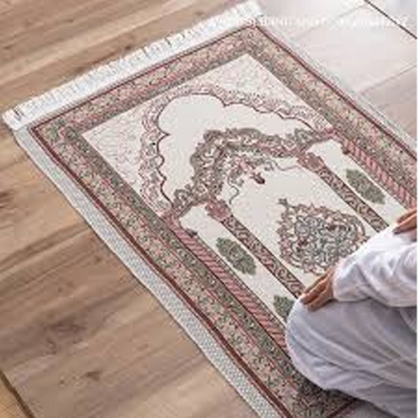 Person praying on a patterned rug with wooden floor and tiled wall in the background