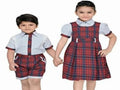 Two children wearing matching school uniforms with a boy in a shirt and shorts and a girl in a dress.