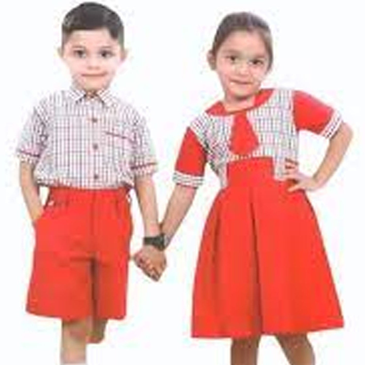Two children holding hands, one in a checkered shirt and red shorts, the other in a red dress with white checkered top.
