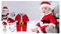 Baby in a Santa Claus outfit with accessories on a light gray background