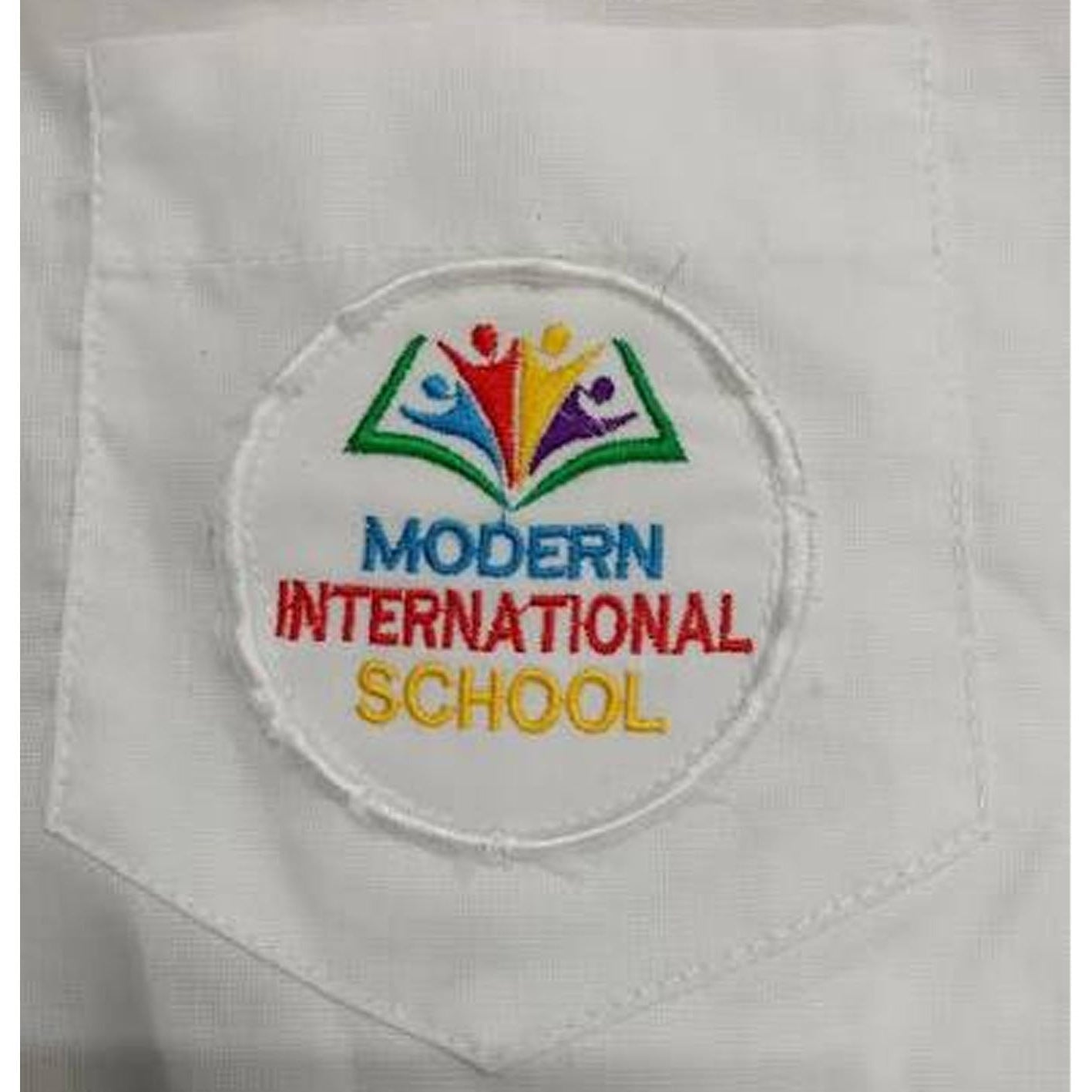 A close-up of a white fabric pocket with a circular embroidered patch reading 'MODERN INTERNATIONAL SCHOOL' in blue, red, and yellow, with a multicolored open-book logo above.