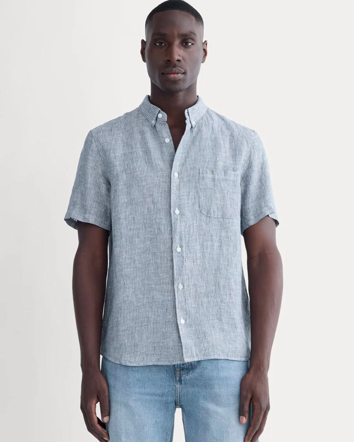 Man wearing a light blue checkered shirt and jeans on a white background