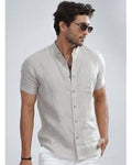 Man wearing a light-colored short-sleeve shirt and sunglasses on a plain background