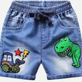 Light blue denim shorts for kids, featuring a dark drawstring waist, front pockets, a green dinosaur patch on the right leg, and a cartoon tractor patch on the left leg.
