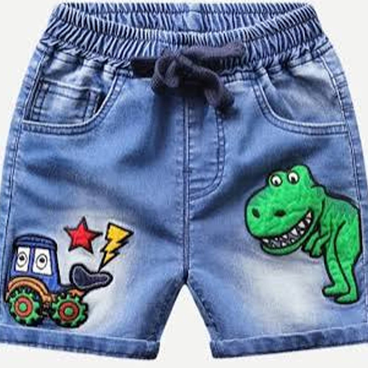 Light blue denim shorts for kids, featuring a dark drawstring waist, front pockets, a green dinosaur patch on the right leg, and a cartoon tractor patch on the left leg.