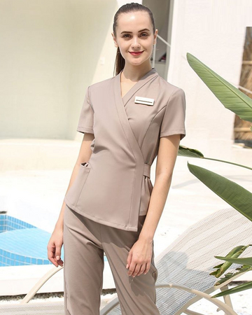 Woman in beige medical or spa uniform standing outdoors with plants and a pool in the background