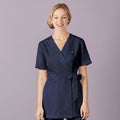 Woman wearing a navy blue uniform against a light purple background