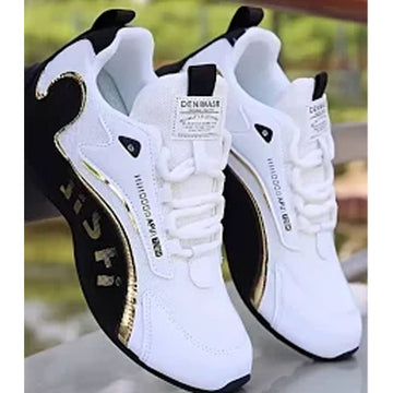 A pair of white low-top sneakers with black side panels, gold metallic accents, and white laces, shown against a blurred outdoor background.
