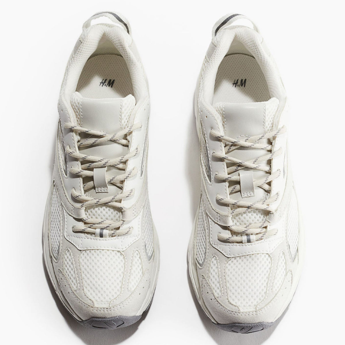 A pair of white and light gray chunky sneakers shown from a top-down view on a white background. The shoes feature a textured mesh and synthetic upper with matching laces, and the brand name 'H&M' is visible on the insole.