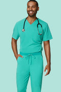A man wearing a matching teal green medical scrub set with a V-neck top, drawstring pants, and a black stethoscope around his neck, standing against a solid light teal background.