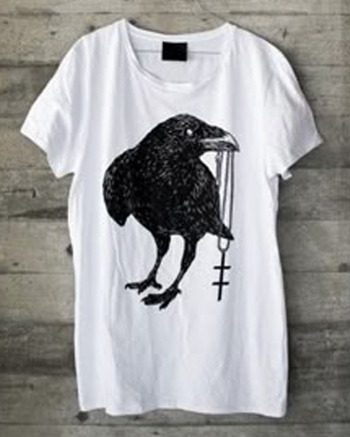 White t-shirt with a black crow design on a wooden surface