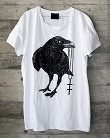 White t-shirt with a black crow design on a wooden surface