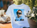 White t-shirt with a graphic of a child wearing sunglasses on a blurred background