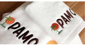 White Embroidered Towel with PAMO on a wooden background