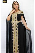 Woman wearing a black dress with gold embroidery on a white background