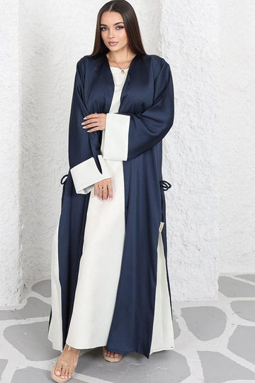 Woman wearing a long, dark blue and white dress against a light background