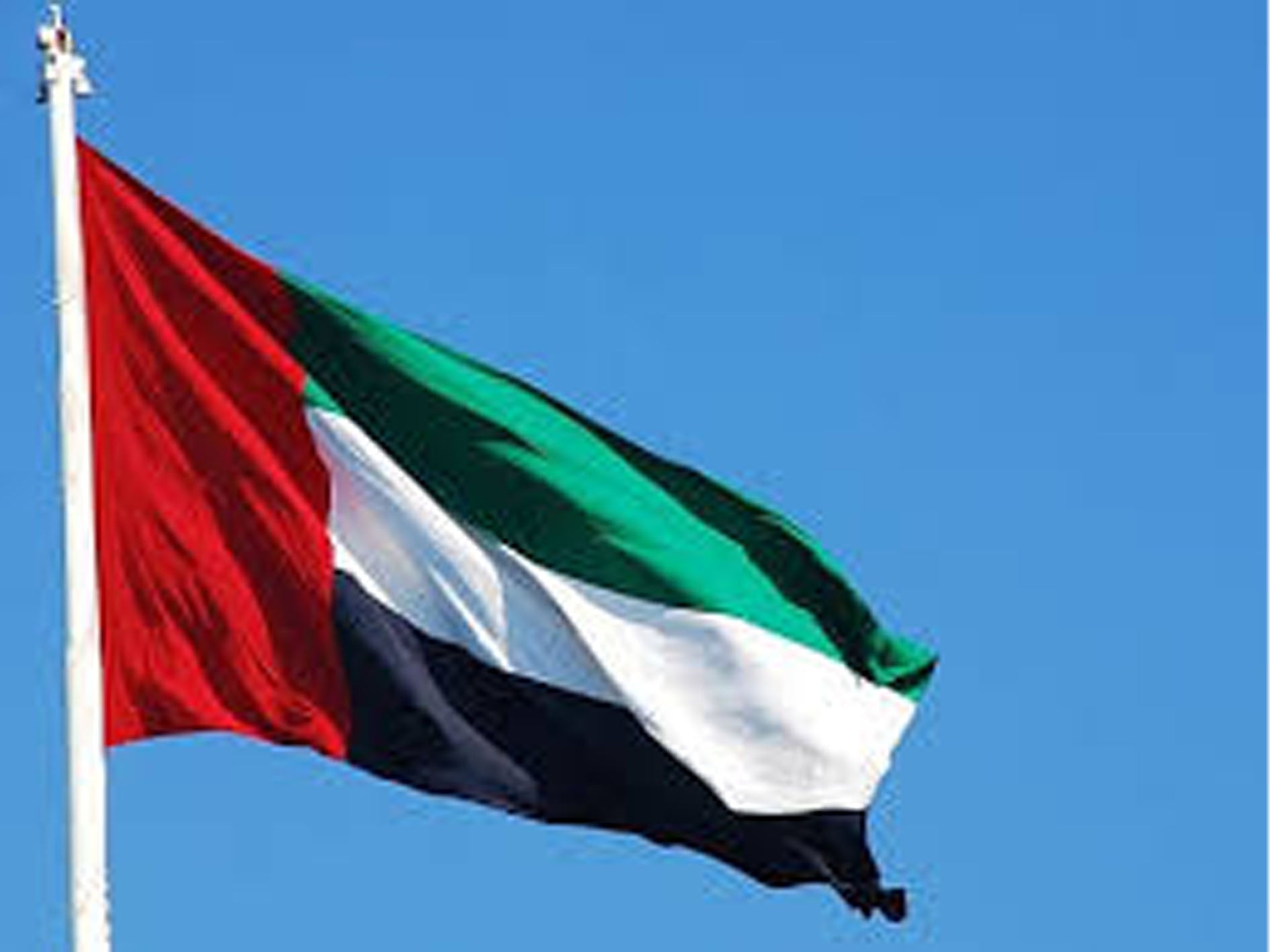 Flag of the United Arab Emirates against a clear blue sky