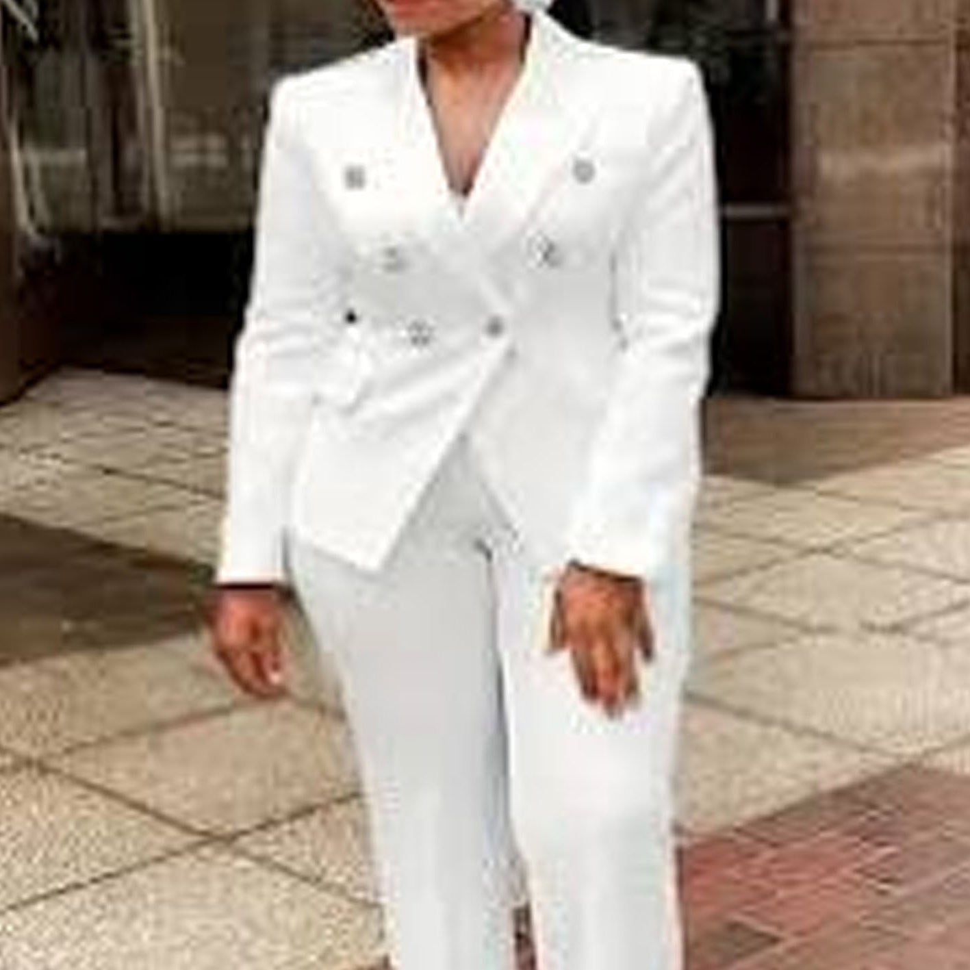 Person wearing a white suit standing on a tiled pavement.