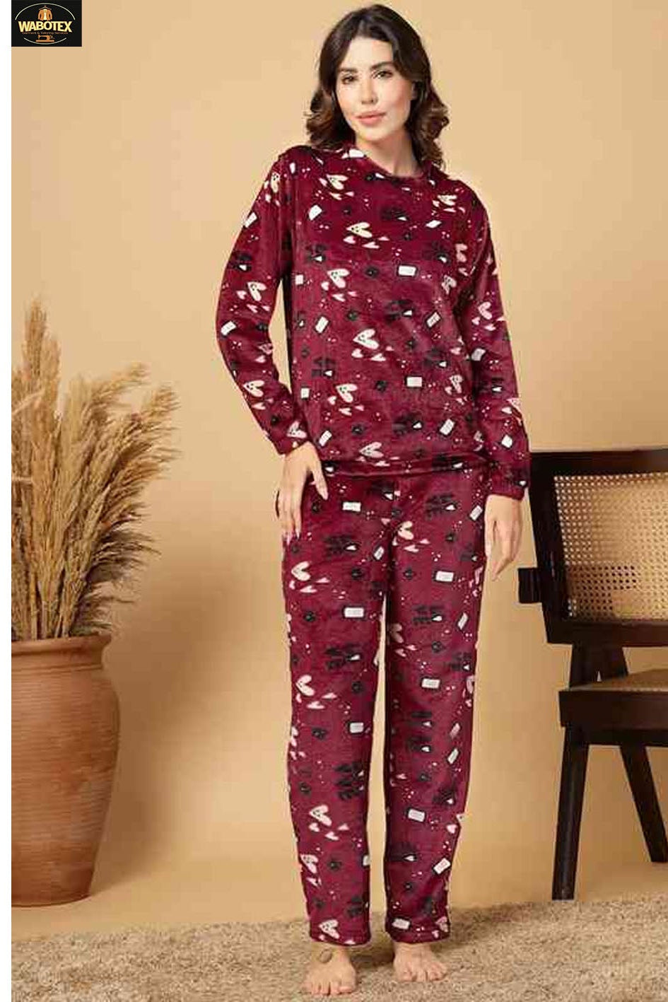 Woman wearing a maroon pajama set with a pattern in a room setting.
