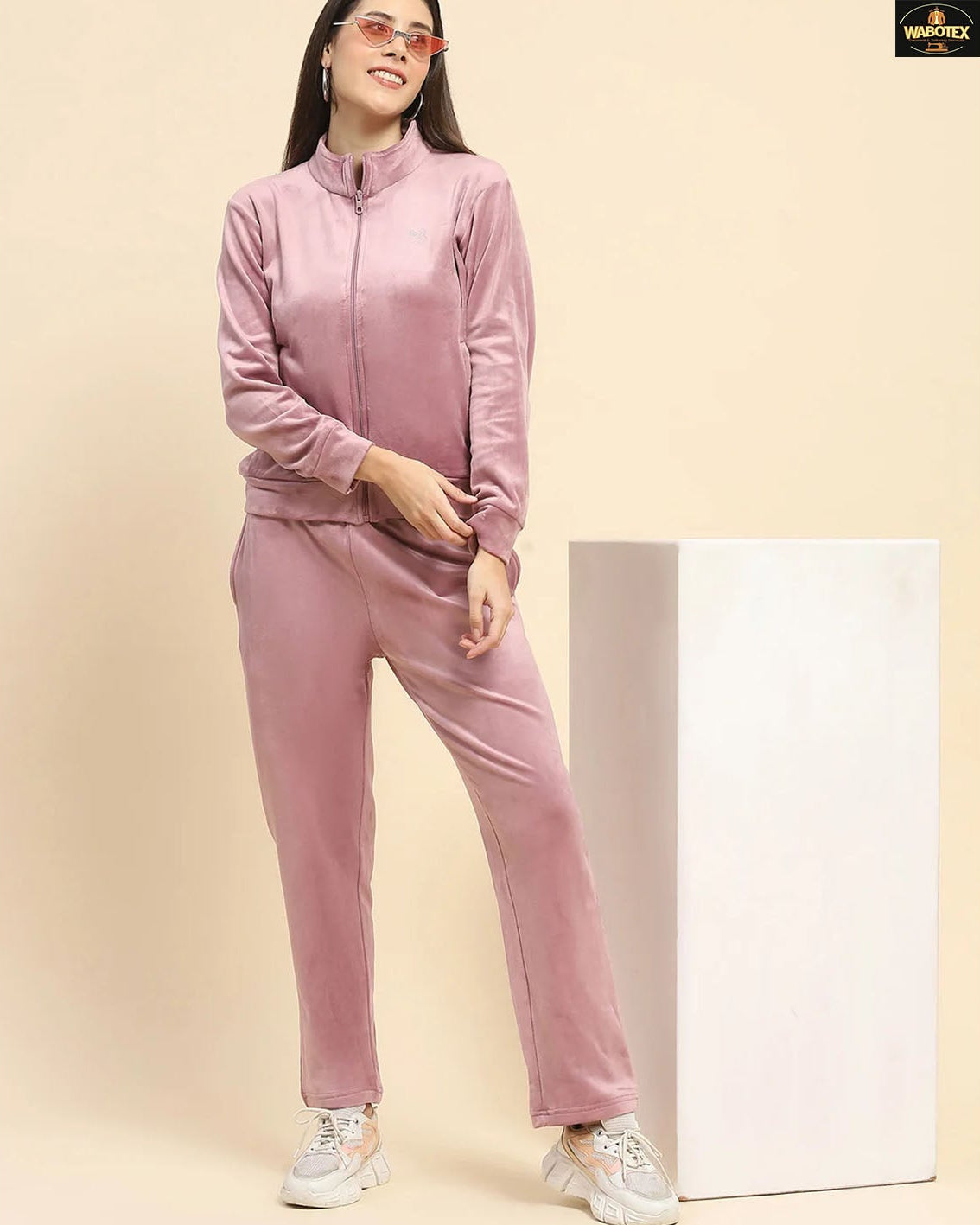 Woman wearing a pink tracksuit against a beige background