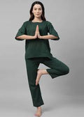 Person wearing a green outfit in a yoga pose on a gray background