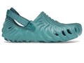 A single teal green waterproof clog shoe with a textured, wavy sole and an adjustable hook-and-loop strap, shown from a side profile on a white background.