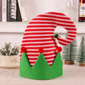 Red and green striped candy cane-shaped decoration on a white surface with a blurred background.