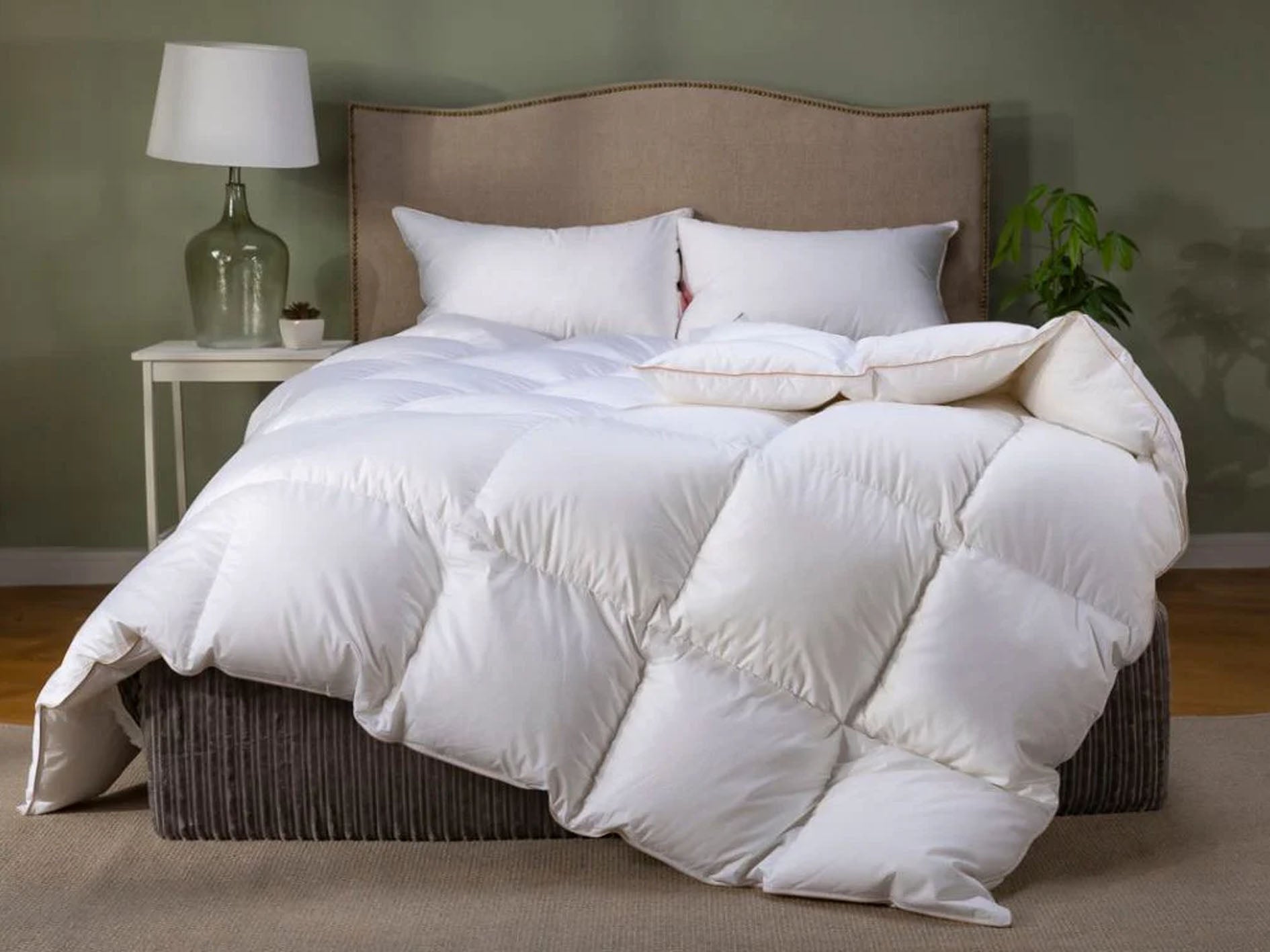 White comforter on a bed with pillows in a bedroom setting