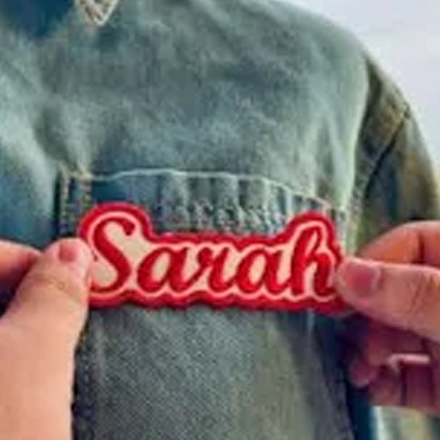 Red patch with 'Sarah' held up against a denim background