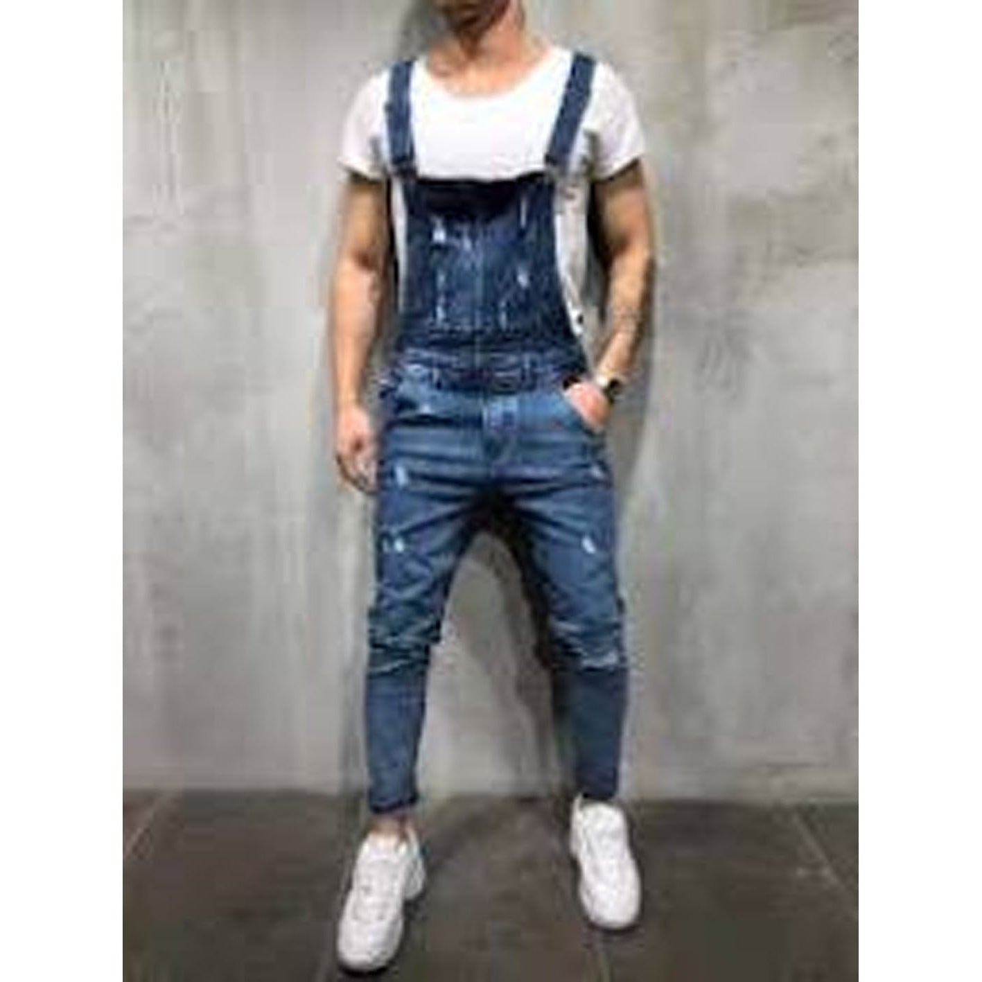 Person wearing blue denim overalls against a gray background