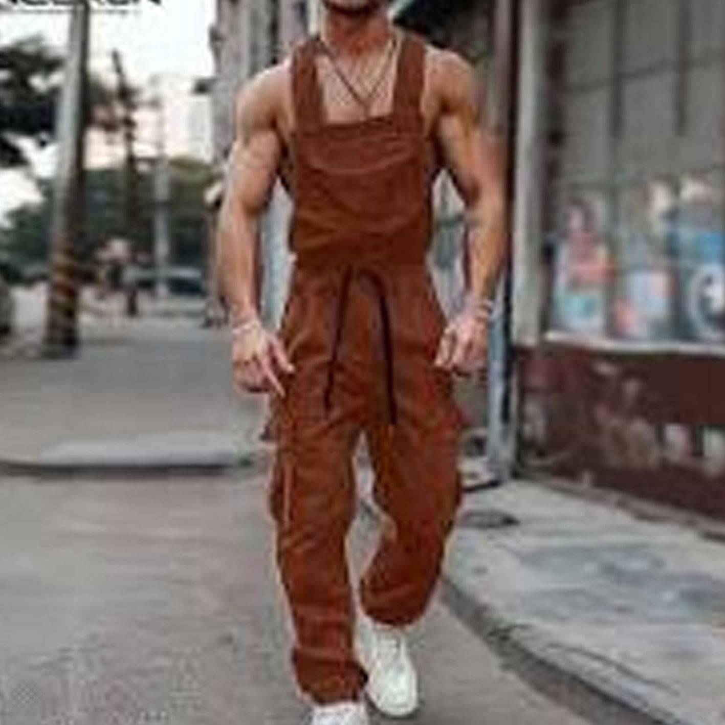Person wearing brown overalls walking on a street.