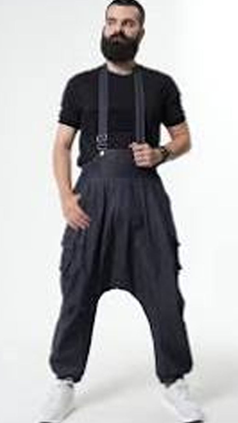 Man wearing black suspenders and harem pants on a white background