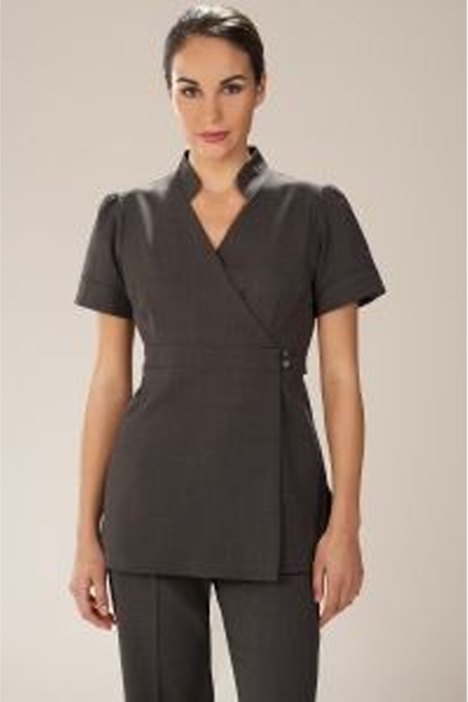 Woman wearing a dark gray professional outfit on a plain background