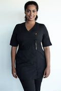 Woman wearing a black scrub set with a logo on a white background