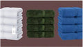 Stacks of white, green, and blue towels on a brown background
