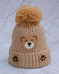 Beige knit hat with bear face and paw prints on a textured light gray background