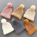 Set of six knitted hats with pom-poms in various colors on a gray background