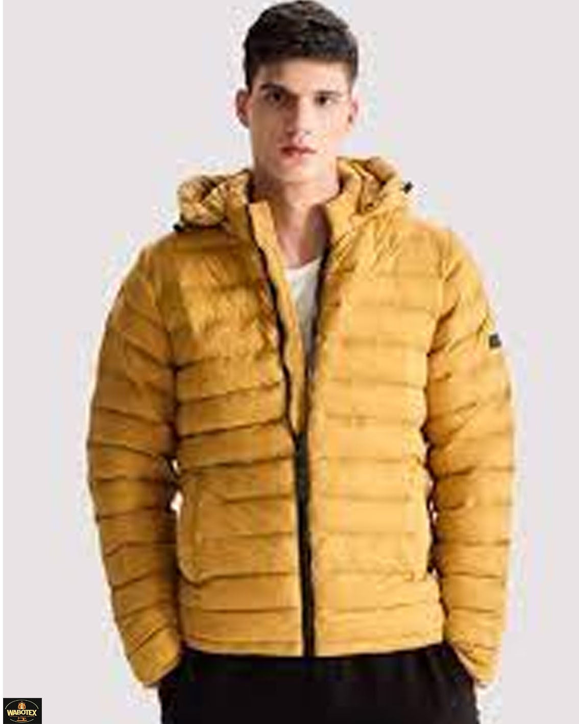 Man wearing a mustard yellow puffer jacket on a light gray background