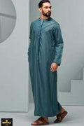 Man wearing a teal traditional outfit in a minimalistic setting