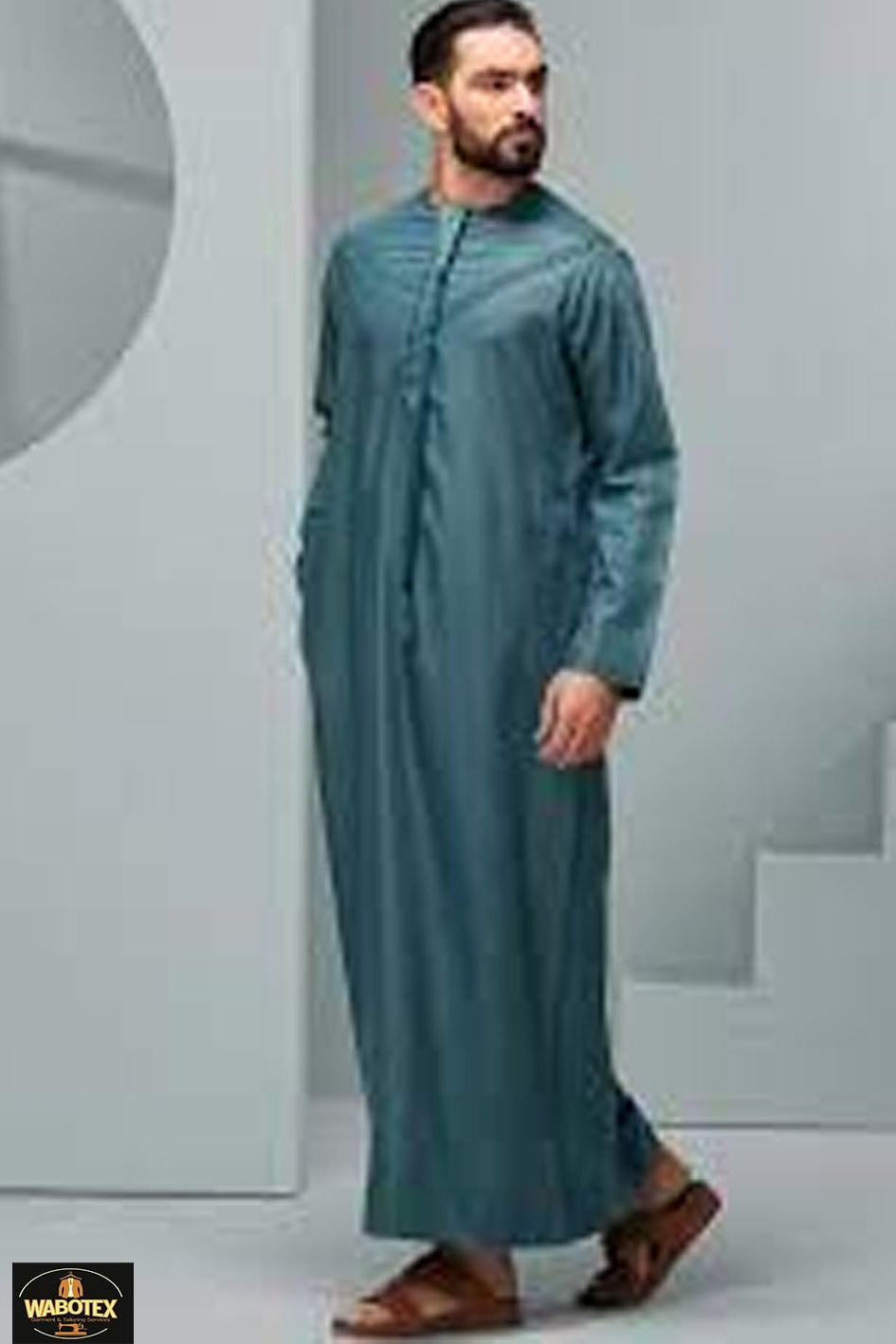 Man wearing a teal traditional outfit in a minimalistic setting